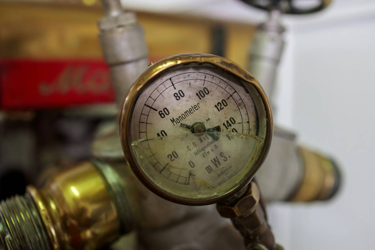 technician performing tool pressure test on stainless steel pressure cooker with gauge and safety valve visible
